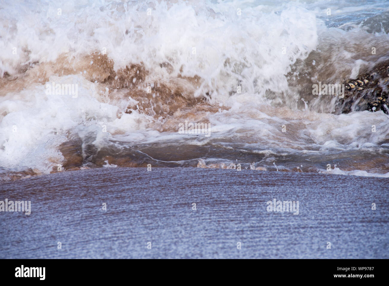 Après-midi forte marée, marée avec des vagues se brisant sur les rochers sur les rochers avec de fortes vagues écumeuses, un ressac, un lavage de côté. Du vrai en colère les vagues. Banque D'Images