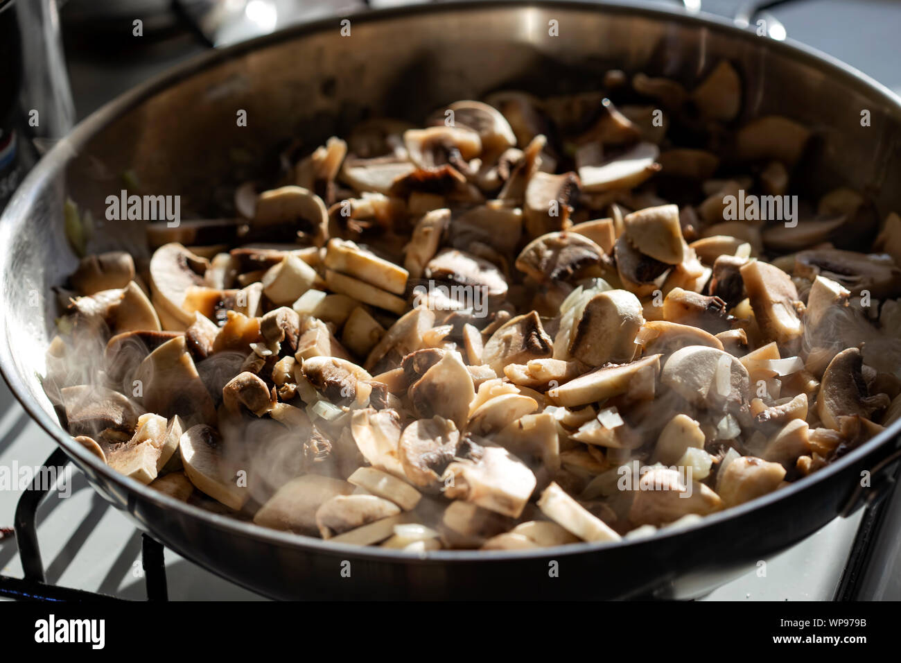 Faire frire l'oignon haché et les champignons dans la poêle avec l'huile d'olive Banque D'Images