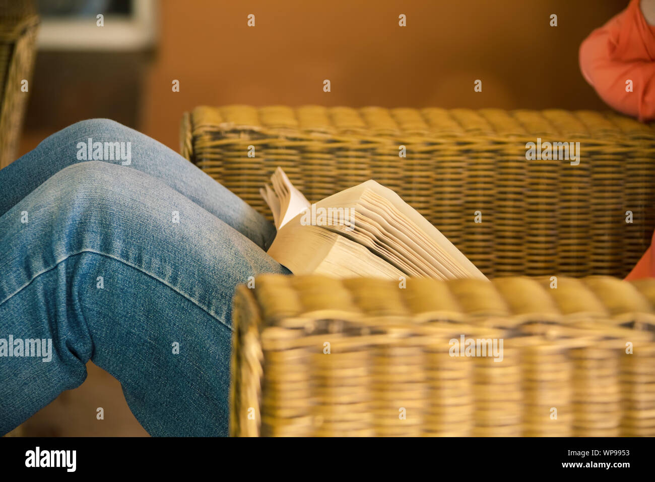 Relaxed woman reading sur un canapé, mobilier en rotin Banque D'Images