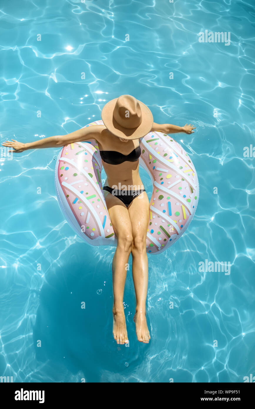 Femme en maillot de bain et chapeau de natation avec anneau gonflable sous  la forme d'un beigne dans l'eau piscine, vue de dessus Photo Stock - Alamy