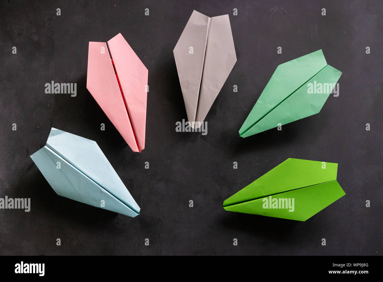 Rangée de certains avions de papier en couleur, la main sur les tables d'origami Banque D'Images