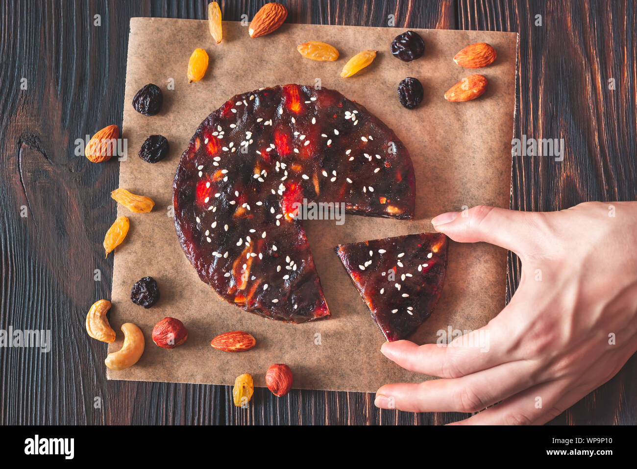 La Main De Femme Avec Une Tranche De Gateau Fruits Presses Et De L Ecrou Sur Le Fond En Bois Photo Stock Alamy