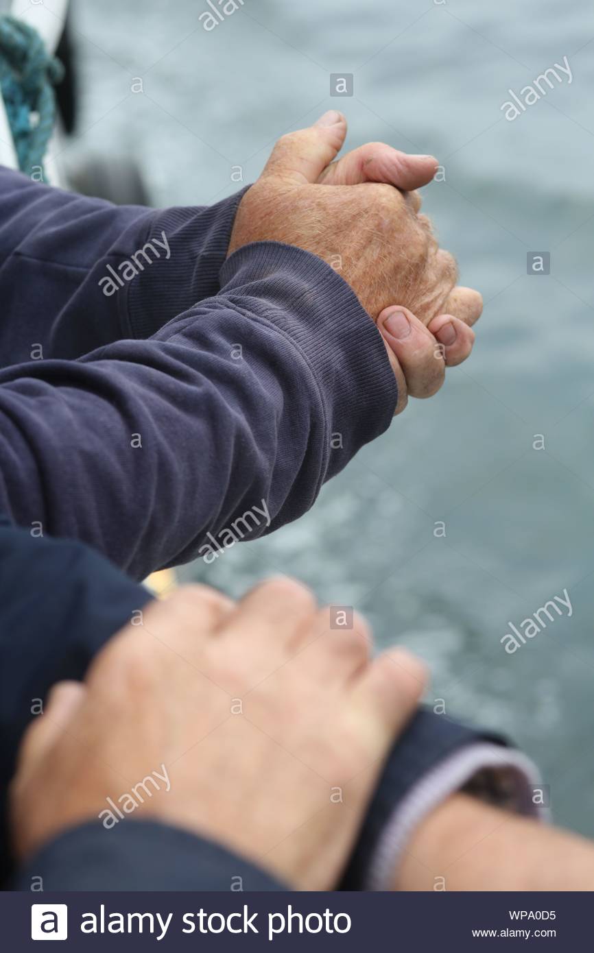 Deux paires de mâles les mains jointes sur le bord d'un bateau dans l'ouest de l'Irlande Banque D'Images