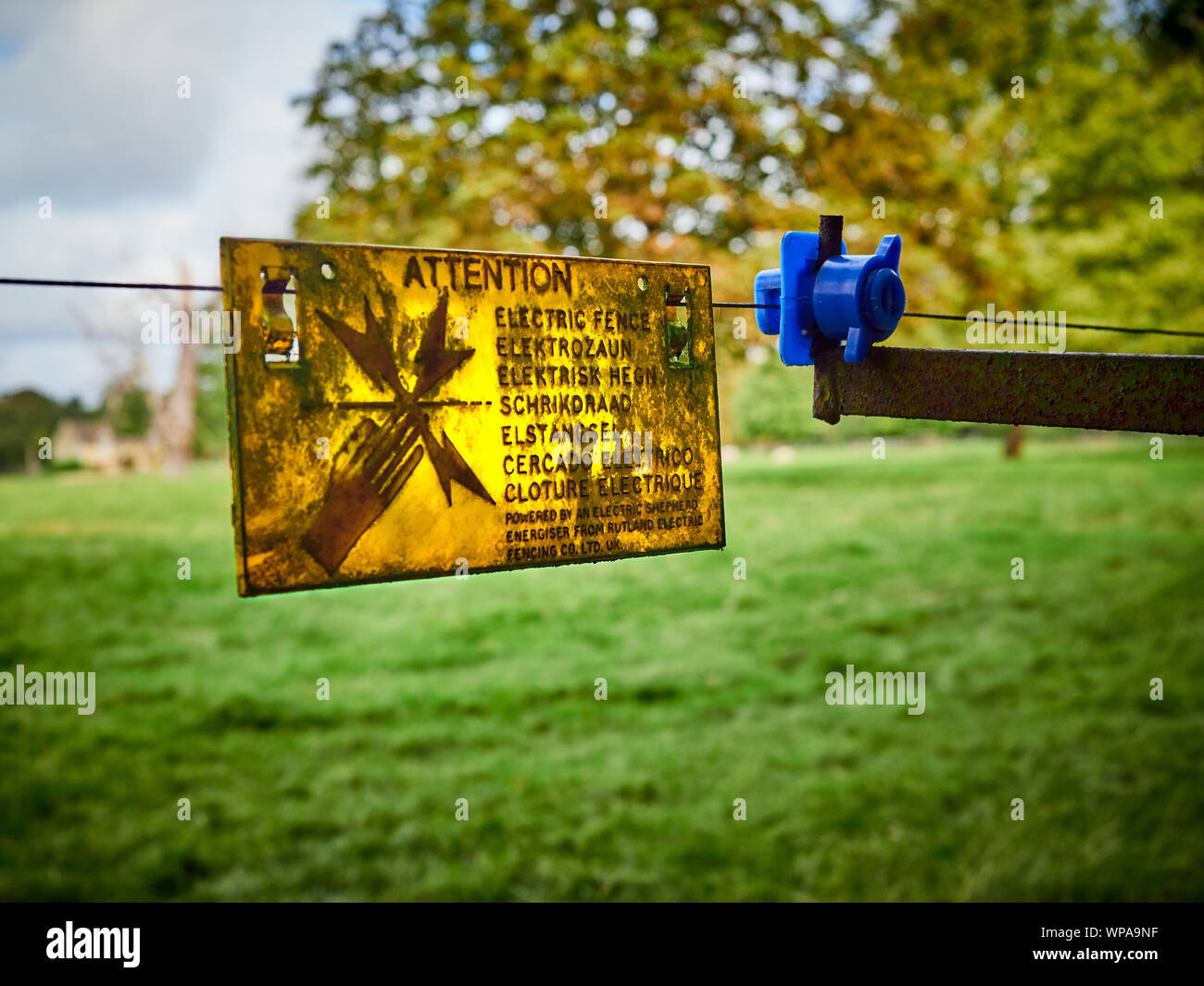 Un panneau d'Avertissement, Attention clôture électrique accroché à côté d'un isolant sur une clôture électrique à côté d'un sentier Banque D'Images