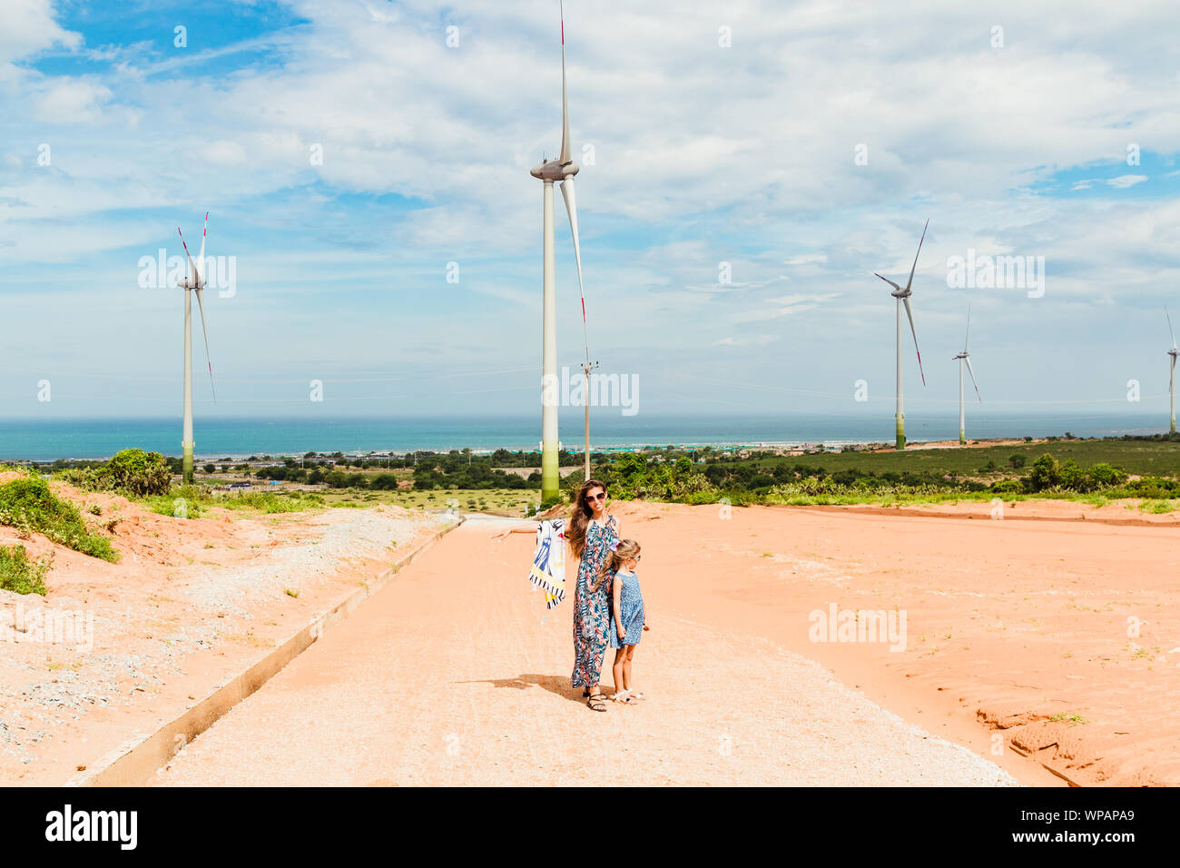Femme et fille se tiennent près de la ferme éolienne de l'énergie propre près de la mer. Phan Rang, au Vietnam. Banque D'Images