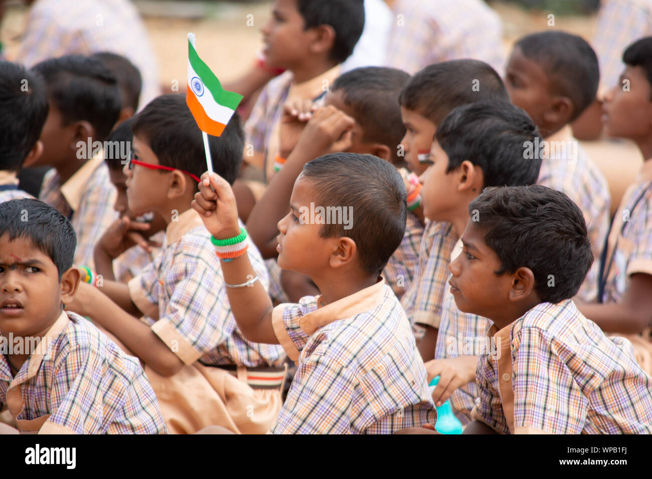 Un groupe d'enfants de l'école élémentaire s'est assis sur la terre par holding drapeau indien dans la main pendant le jour de l'indépendance de l'Inde Banque D'Images