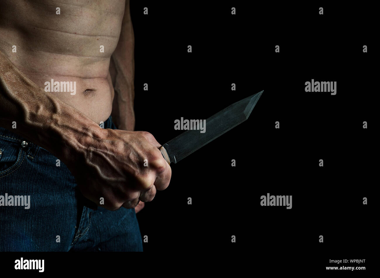 Un homme avec un couteau à la main dans l'obscurité. Banque D'Images