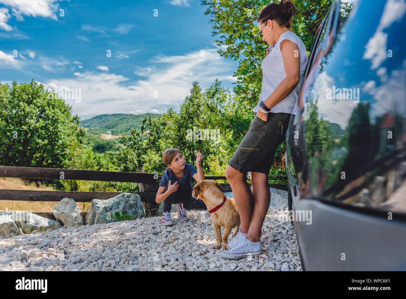 Famille sur un voyage sur la route en faisant une pause pour étirer les jambes après avoir conduit Banque D'Images Famille sur un voyage sur la route en faisant une pause pour étirer les jambes après avoir conduit Banque D'Images