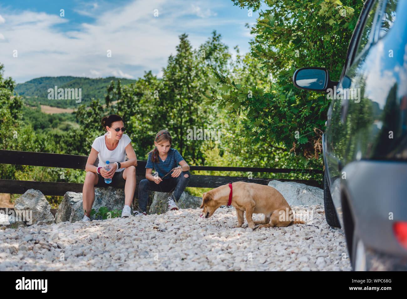 Mère et fille sur un road trip avec chien prendre une pause et assis sur un rocher Banque D'Images Mère et fille sur un road trip avec chien prendre une pause et assis sur un rocher Banque D'Images