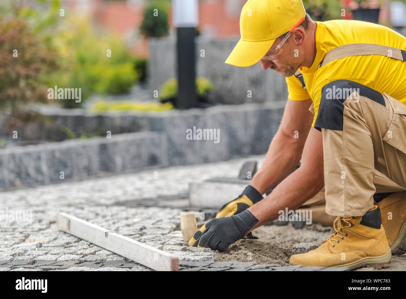 Granit Pavage résidentiel brique par Caucasian Construction Worker. Banque D'Images