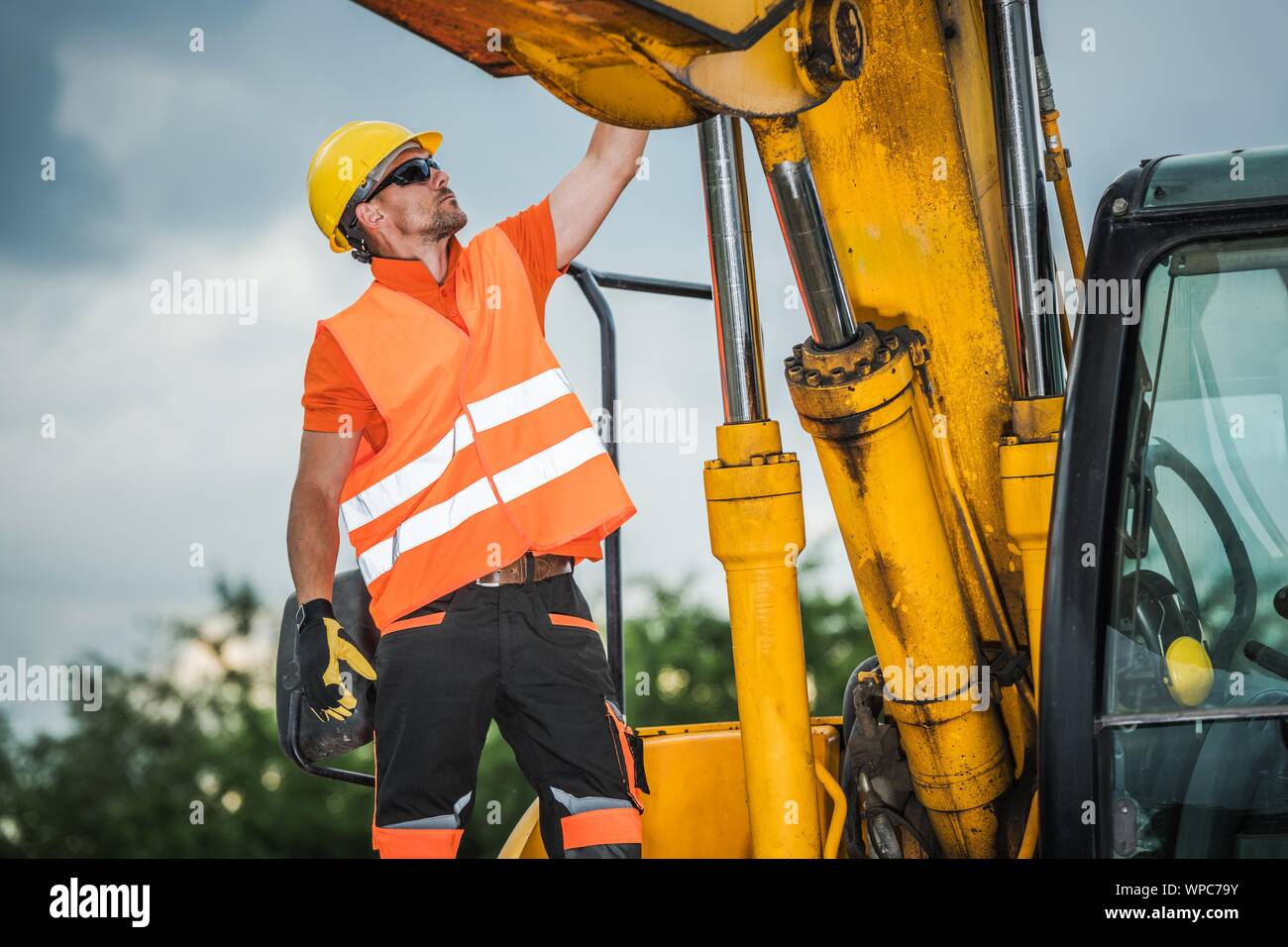 Conducteur d'excavatrice moderne. Caucasian Construction Worker et les machines industrielles. Banque D'Images