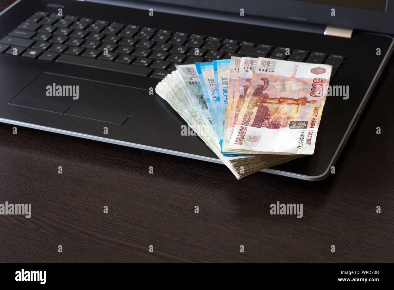 Fédération de monnaie de papier pliée en ventilateur disposés sur clavier d'ordinateur portable. Table marron foncé avec copie espace. Haut angle view. Billets de différentes dénominations. Banque D'Images