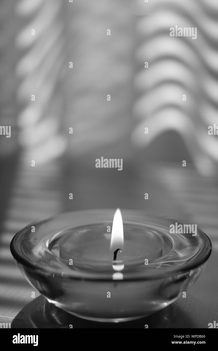 Petite chandelle brûle dans un chandelier en verre rond sur la table, photo nb Banque D'Images