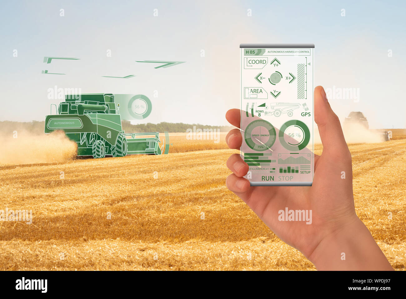 Agriculteur utilise un smartphone transparent futuriste pour contrôler l'ensileuse autonome. Concept d'agriculture intelligente. Banque D'Images