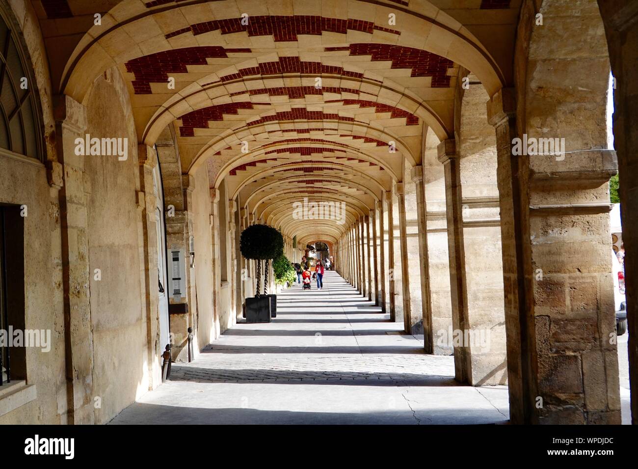 Shoppers sous l'arcade, un passage couvert, sur une paisible dimanche matin à la Place des Vosges dans le Marais, Paris, France. Banque D'Images