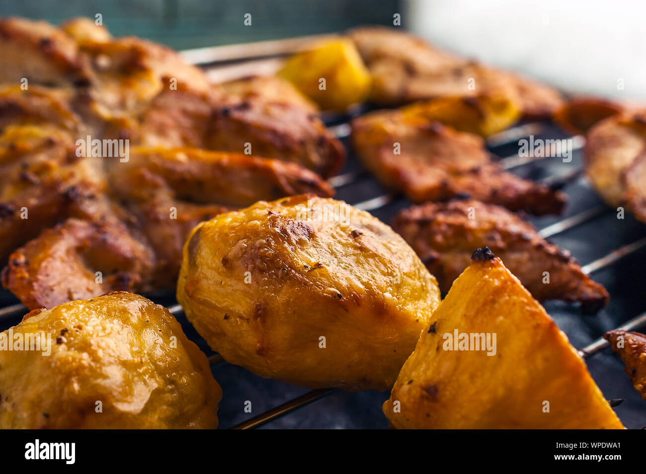 Tranches de poulet et pommes de terre sur la grille de cuisson en acier inoxydable. Banque D'Images