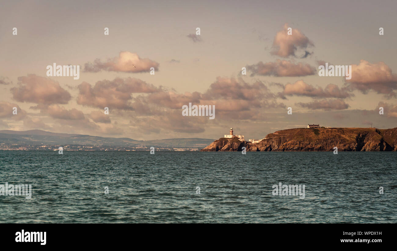 Howth phare à l'entrée de la baie de Dublin situé au Rochers de Howth Head avec Dublin sur l'arrière-plan. Mer d'Irlande. Banque D'Images