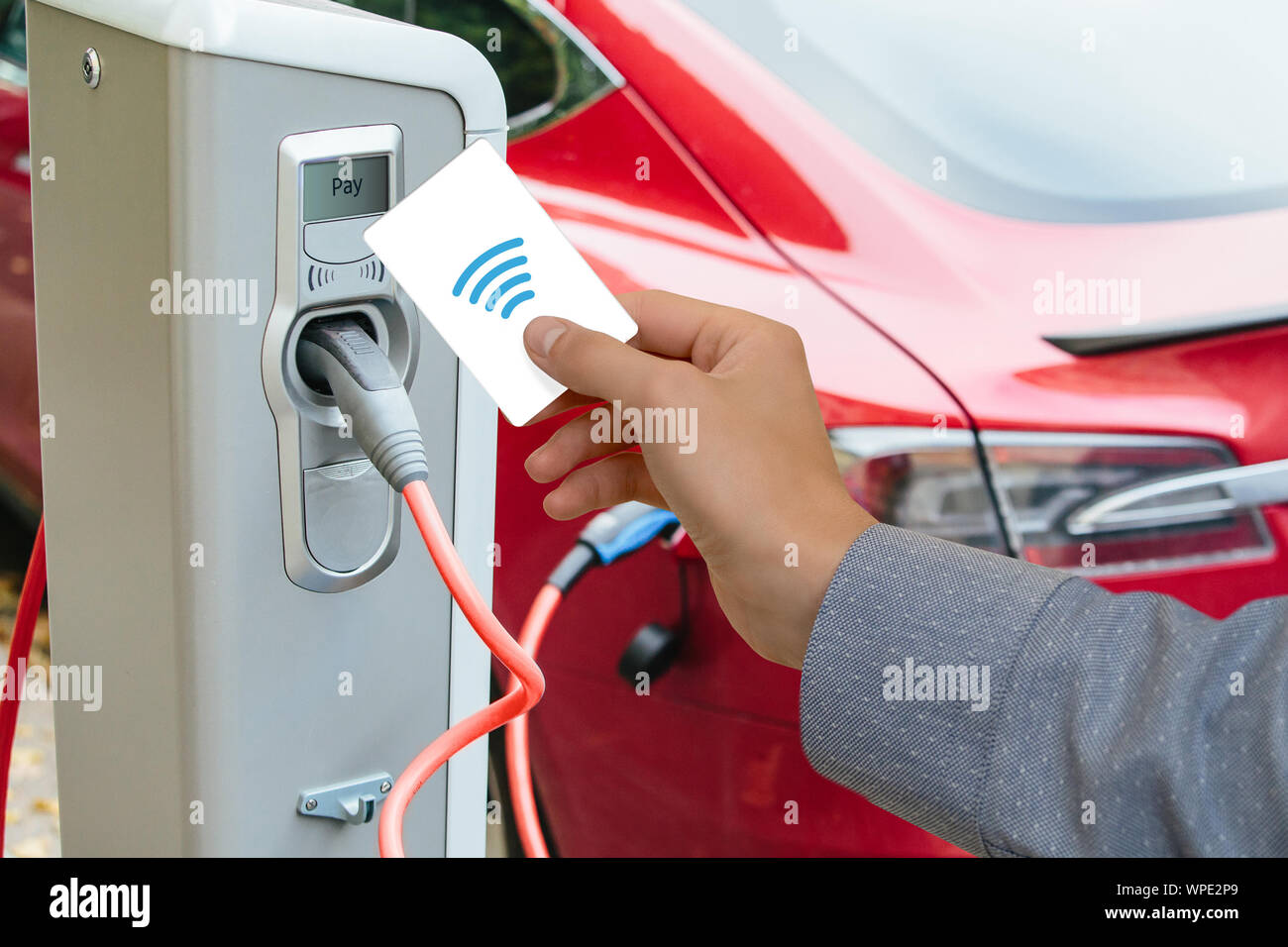 Un homme paie pour la recharge d'une voiture électrique. Banque D'Images