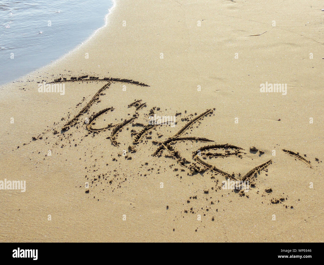 Plage de sable avec des vagues et le mot "Turkey" écrit en allemand dans le sable Banque D'Images