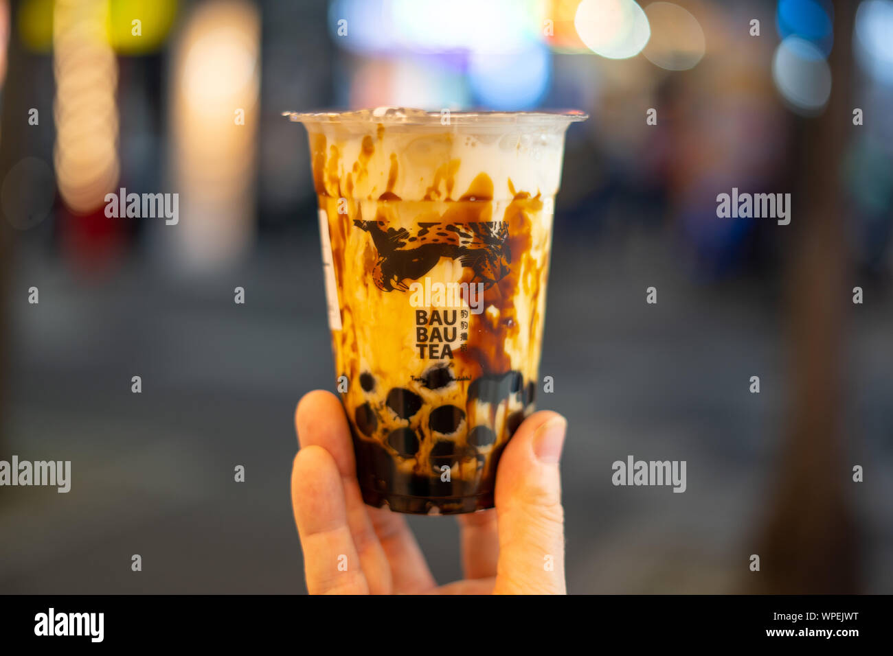Main tenant tasse en plastique noir de Lait Sucre bubble tea (thé) avec arrière-plan flou floue Bau Bau (plateau) Banque D'Images
