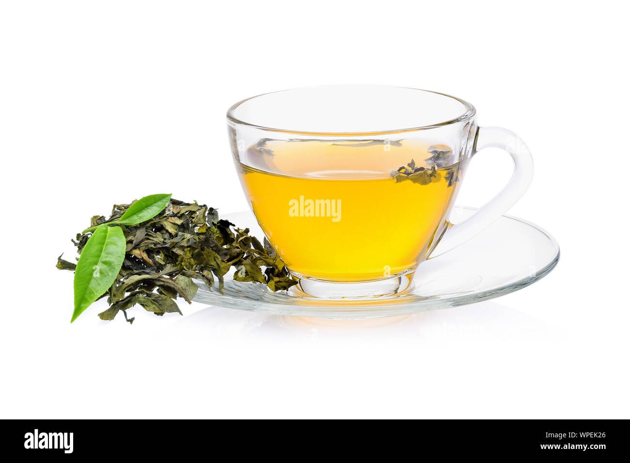 Feuilles de thé vert avec un verre de thé sur fond blanc Banque D'Images