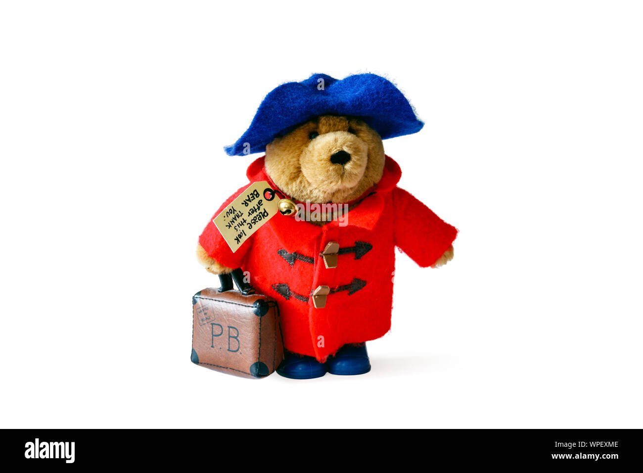 Une peluche Ours Paddington avec red duffel coat, blue hat et valise, isolé sur un fond blanc. Banque D'Images