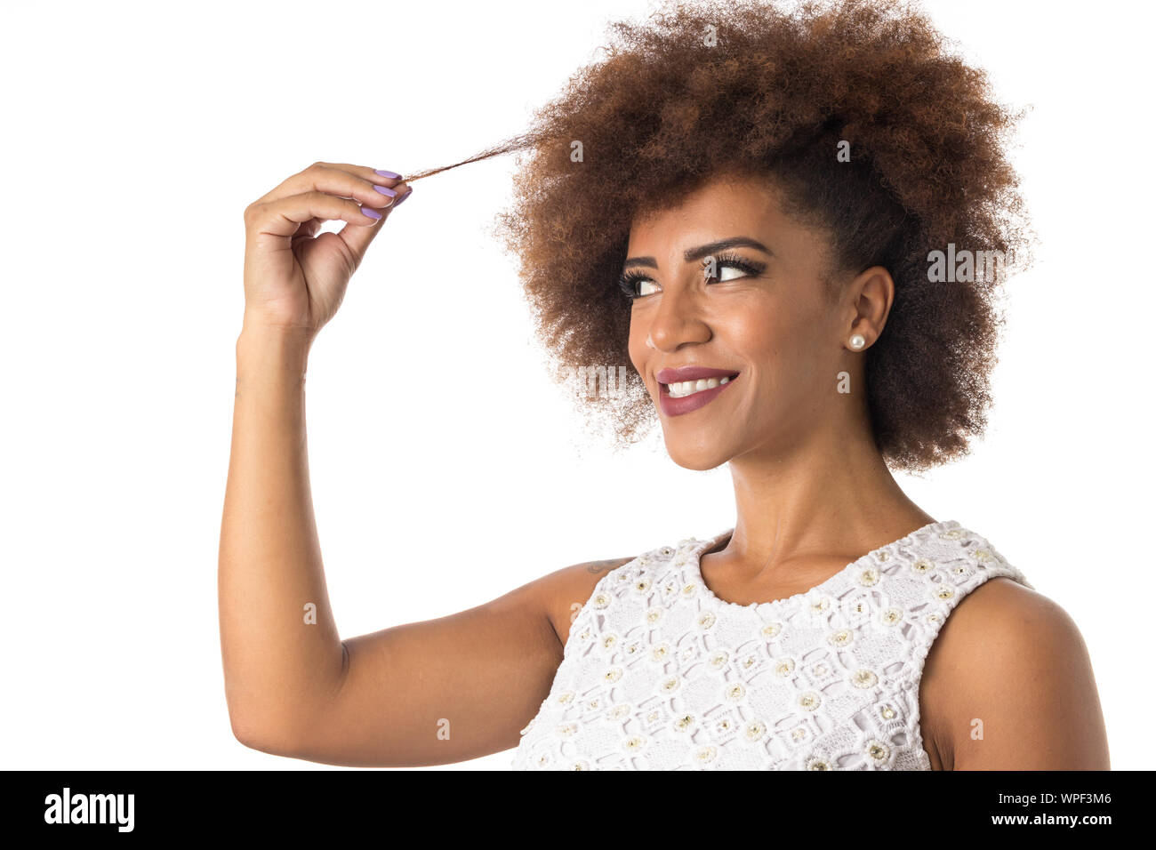 Portrait de cheveux afro brésilien noir girl smiling gaiement et tenir les cheveux. Concept de soins capillaires. Standing against white background. Banque D'Images