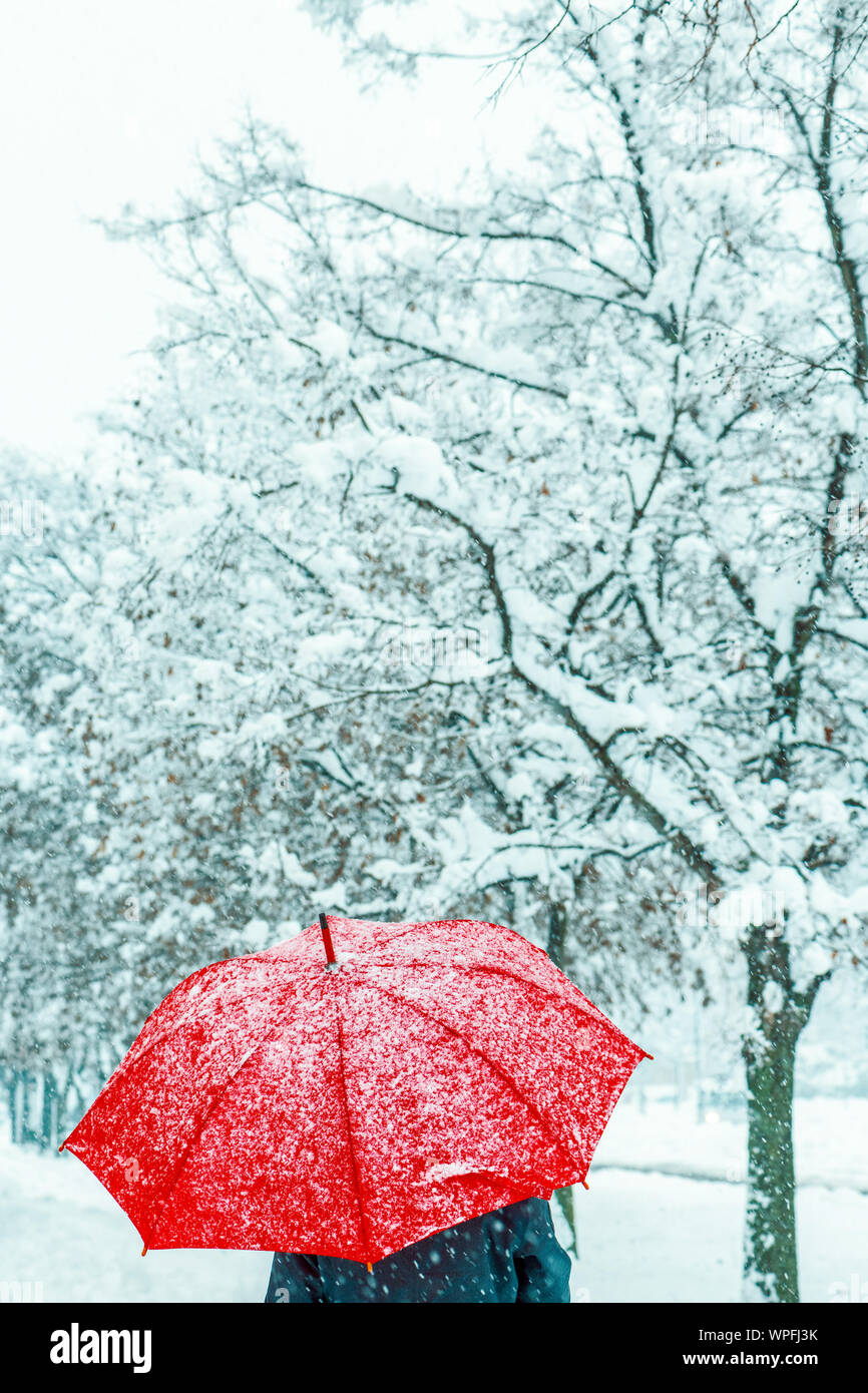 Femme sous parapluie rouge dans la neige profiter de la première neige de la saison d'hiver Banque D'Images