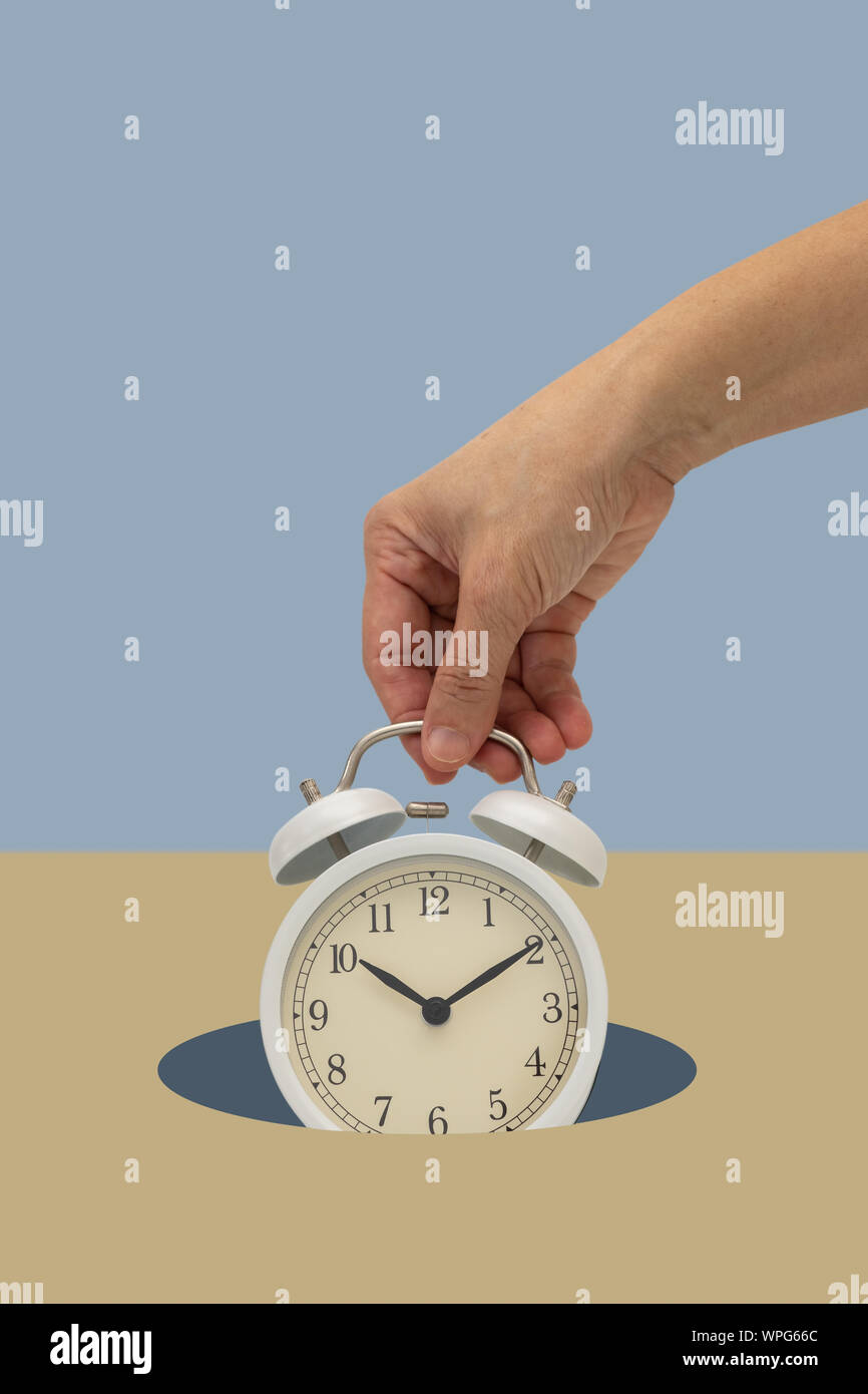 Hand holding white vintage réveil sur fond bleu tomber vers le bas. Temps concept minimal. Banque D'Images