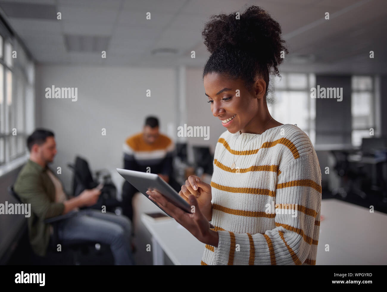 Portrait of a casual dressed african american female executive using digital tablet in office moderne avec des collègues travaillant dans l'arrière-plan Banque D'Images