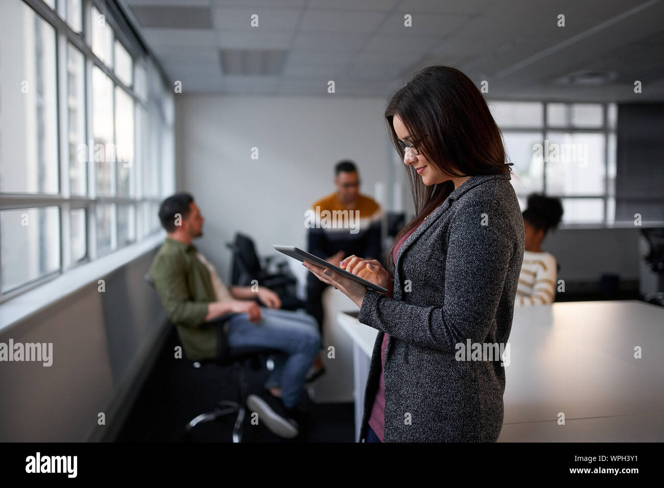 Smiling young businesswoman using digital tablet in alors qu'au bureau Banque D'Images