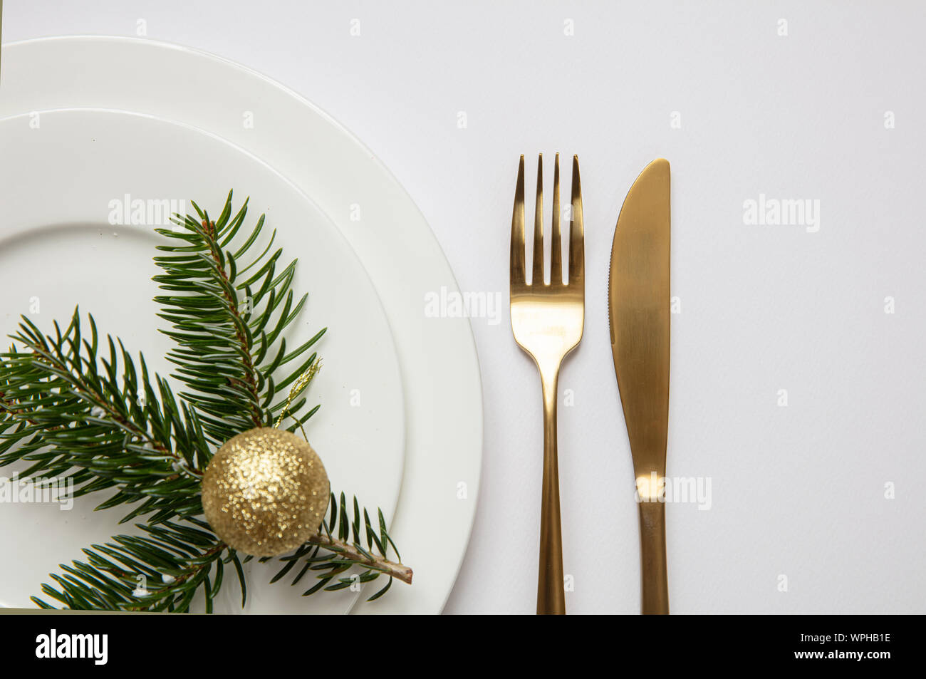 Noël, Nouvel An dîner table. Rameau de sapin blanc sur ensemble de plats, fond blanc, vue du dessus Banque D'Images