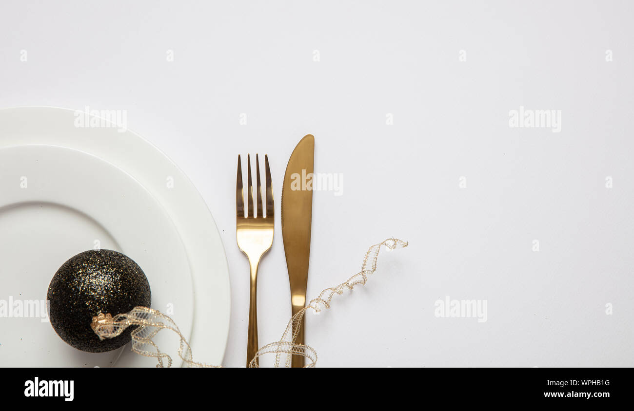 Table de dîner de Nouvel An, Boule de Noël avec le ruban et couverts sur l'ensemble de la vaisselle blanche, fond blanc, vue du dessus Banque D'Images