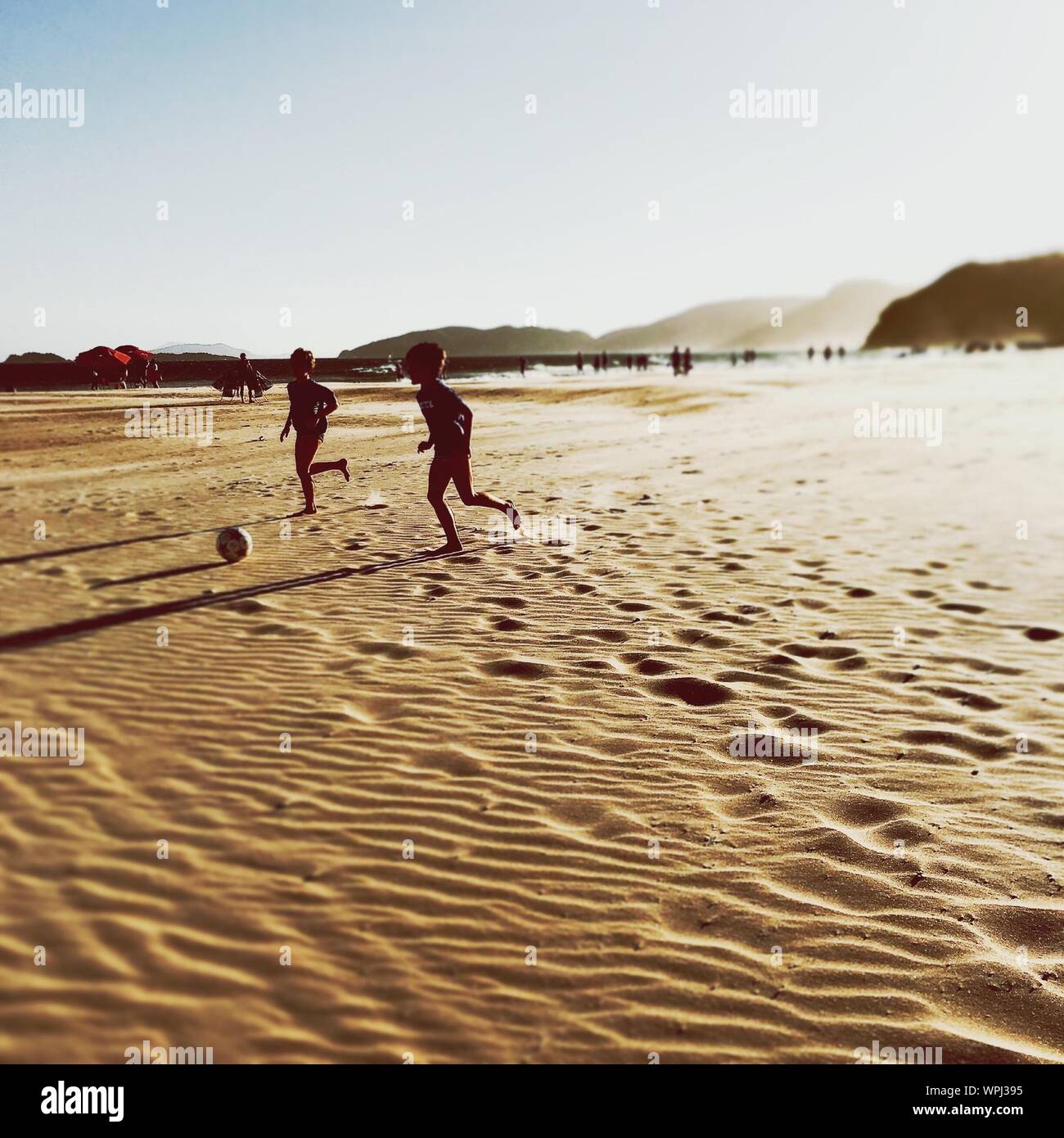 Boys Playing With ball sur plage de sable Banque D'Images