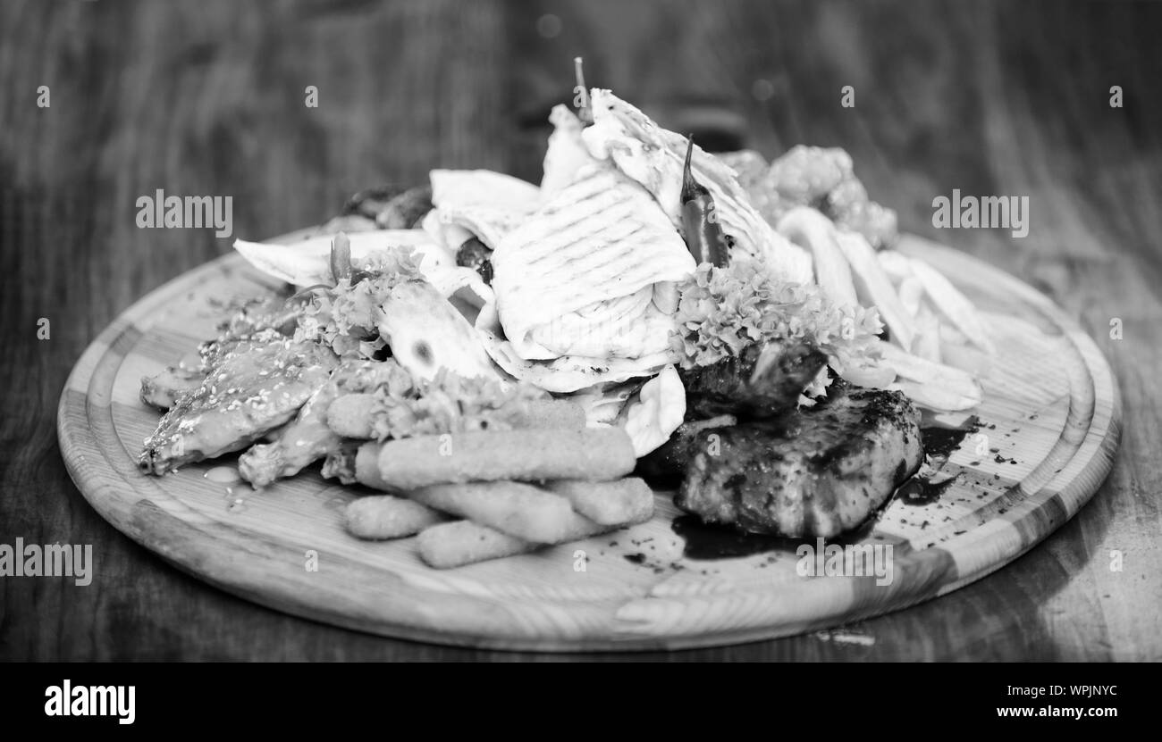 Planche de bois avec beaucoup de frites et bâtonnets de poisson viande burrito steak servi avec une salade. Menu snack-bar. Calories élevé pour le groupe d'amis. De délicieux en-cas savoureux. Les repas au restaurant. Snack pour la bière. Banque D'Images