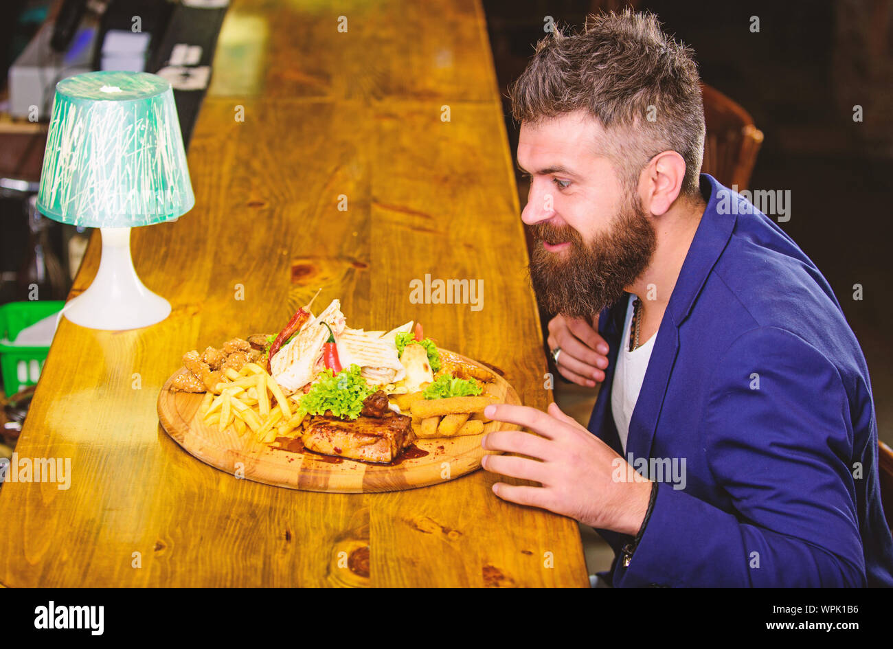 Woman costume formel s'asseoir à comptoir bar. L'homme a reçu de pommes de terre frites repas avec viande et poisson, lavash. Profitez de repas. Il méritent de délicieux repas. Des calories. Vous pourrez vous détendre après une dure journée de travail. Banque D'Images