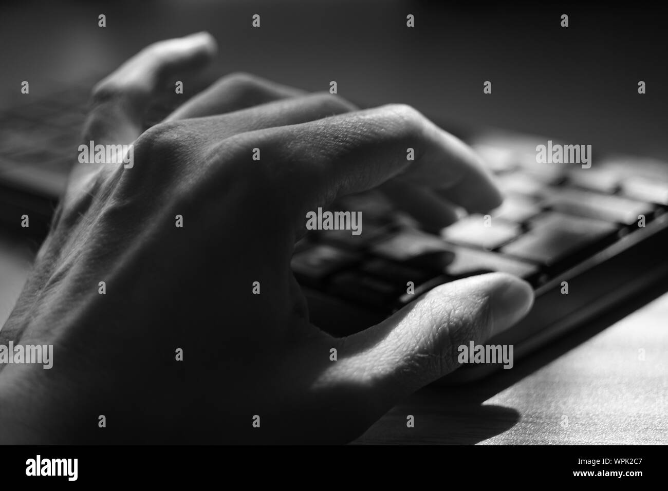 Les jeunes main humaine est saisie au clavier, selective focus, photo en noir et blanc. Banque D'Images