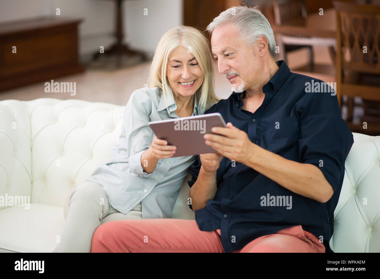D'âge mûr à l'aide d'une tablette numérique dans leur appartement Banque D'Images