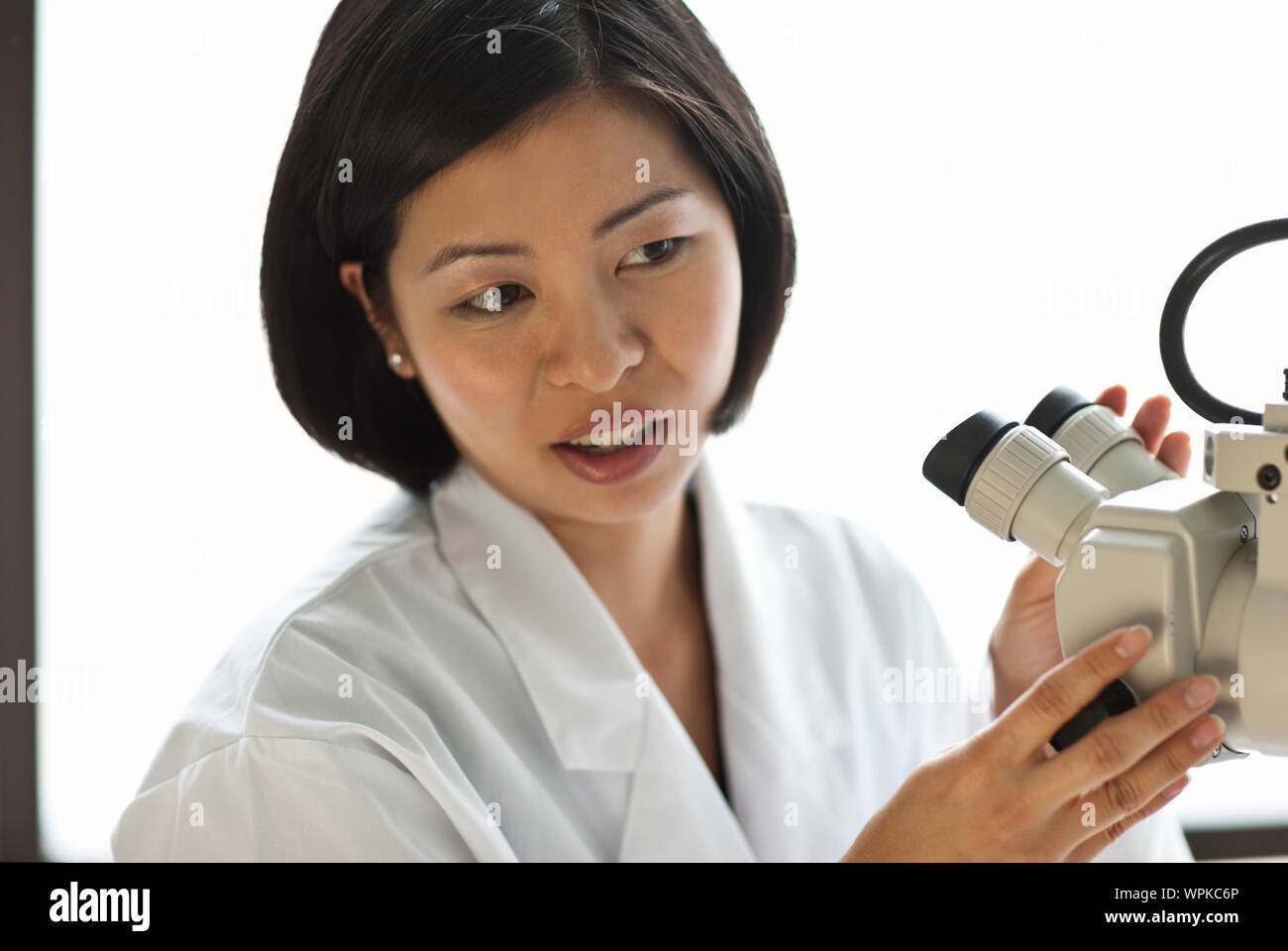 Femme médecin regarder quelque chose à travers un microscope. Banque D'Images