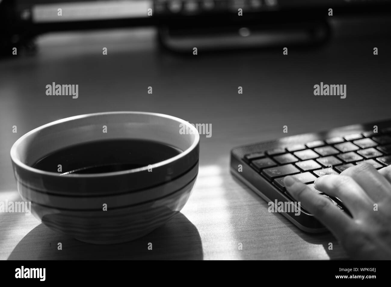 Travail indépendant avec tasse de thé et le clavier sur la table, de l'environnement de travail, selective focus, photo en noir et blanc. Banque D'Images