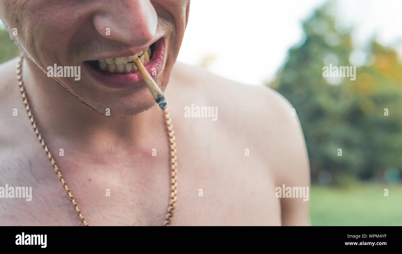 Le jeune fumeur de marijuana médicale à l'extérieur. conjointe Le jeune homme fumer du cannabis blunt, close-up. Le cannabis est un concept de médecine de fines herbes. Banque D'Images