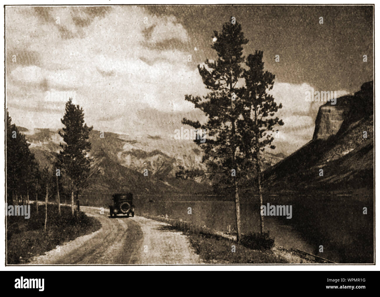 Un magazine 1924 photographie montrant une voiture d'époque sur une route longeant le lac Minnewanka, ('eau des esprits', Canada. Maintenant, le 2e plus long Lake dans les parcs de montagne des Rocheuses canadiennes en raison de la construction d'un barrage Banque D'Images