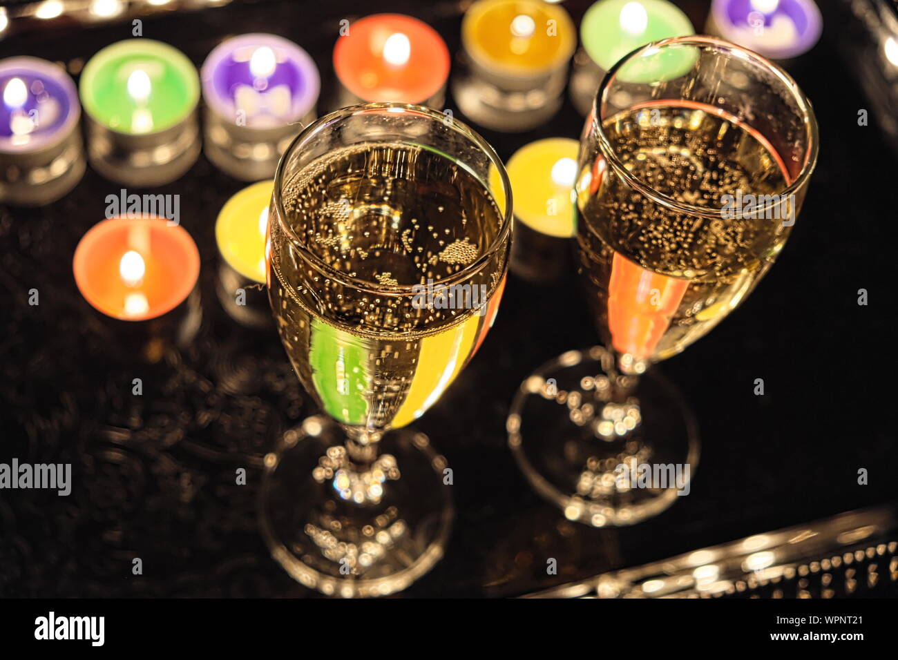 Deux verres de champagne sur un plateau avec des bougies de couleur Banque D'Images