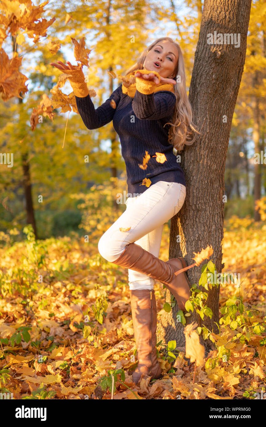 La fille repose sur un arbre et est photographiée au coucher du soleil dans des vêtements de cow-boy, des bottes brunes Banque D'Images