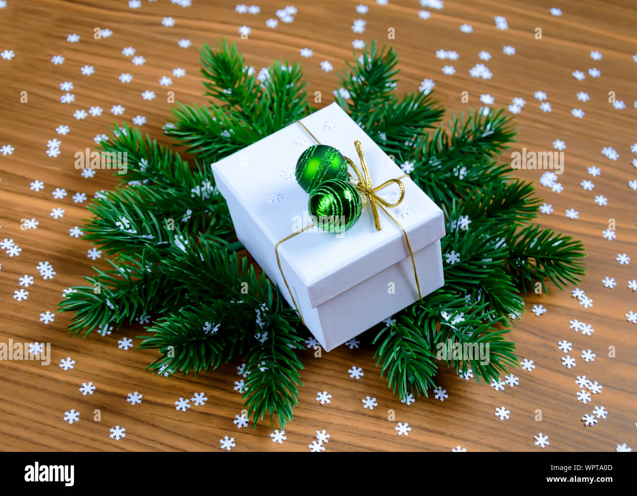 Boîte cadeau de Noël blanc élégant avec des boules vertes sur les branches de sapins et fond de bois Banque D'Images