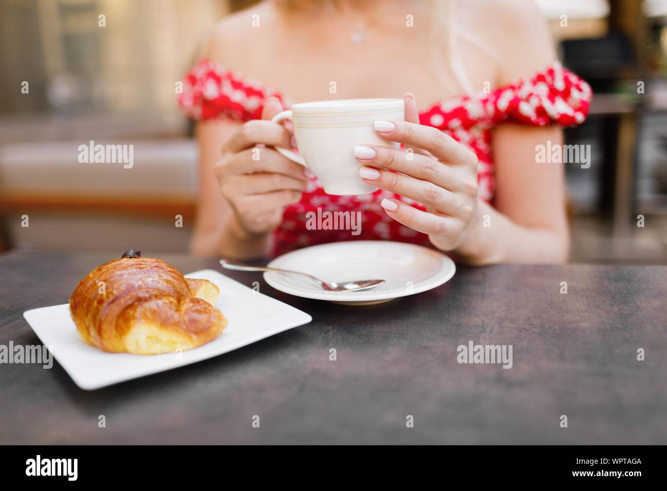 Jeune femme ayant le petit déjeuner italien avec des croissants et un café Banque D'Images