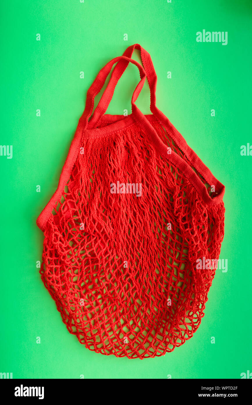 Sac shopping rouge sur fond vert. Concept zéro déchet plastique et de concept. Banque D'Images