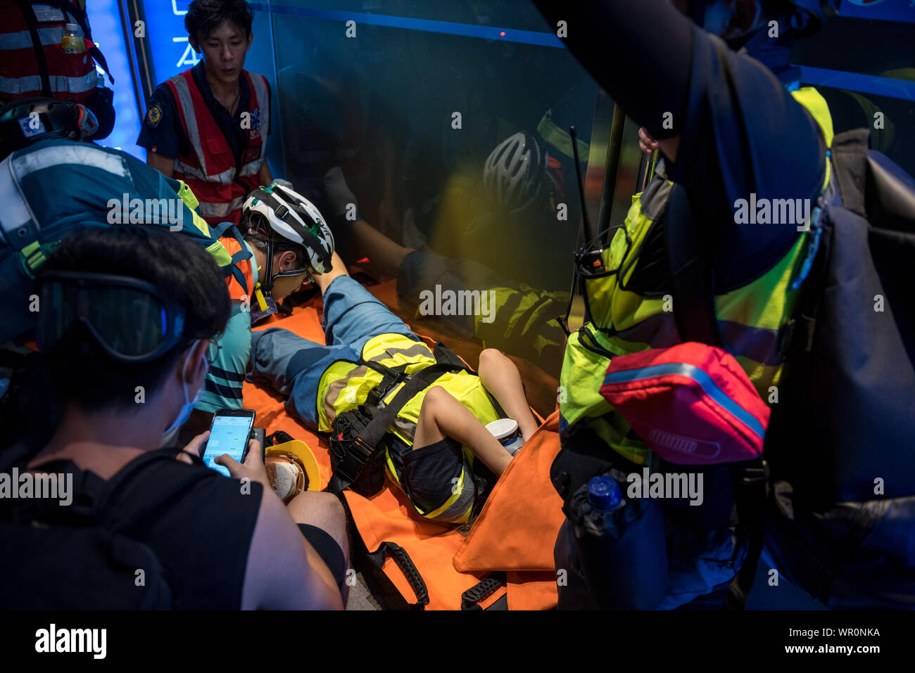 Un secouriste bénévole est traité par le personnel médical après être frappé par un Pouf poire tiré par la police lors de la manifestation.manifestants encore une fois occupé rues, près de l'île en réponse à la station de police d'assaut la gare la semaine précédente. Les manifestants ont continué à exiger la MTR Corporation pour libérer des images de vidéosurveillance de l'incident et sont retournés pour protester à la station presque chaque nuit depuis. La police a tiré plusieurs obus de pouf avant de mener une opération de dispersion et de faire plusieurs arrestations. Banque D'Images