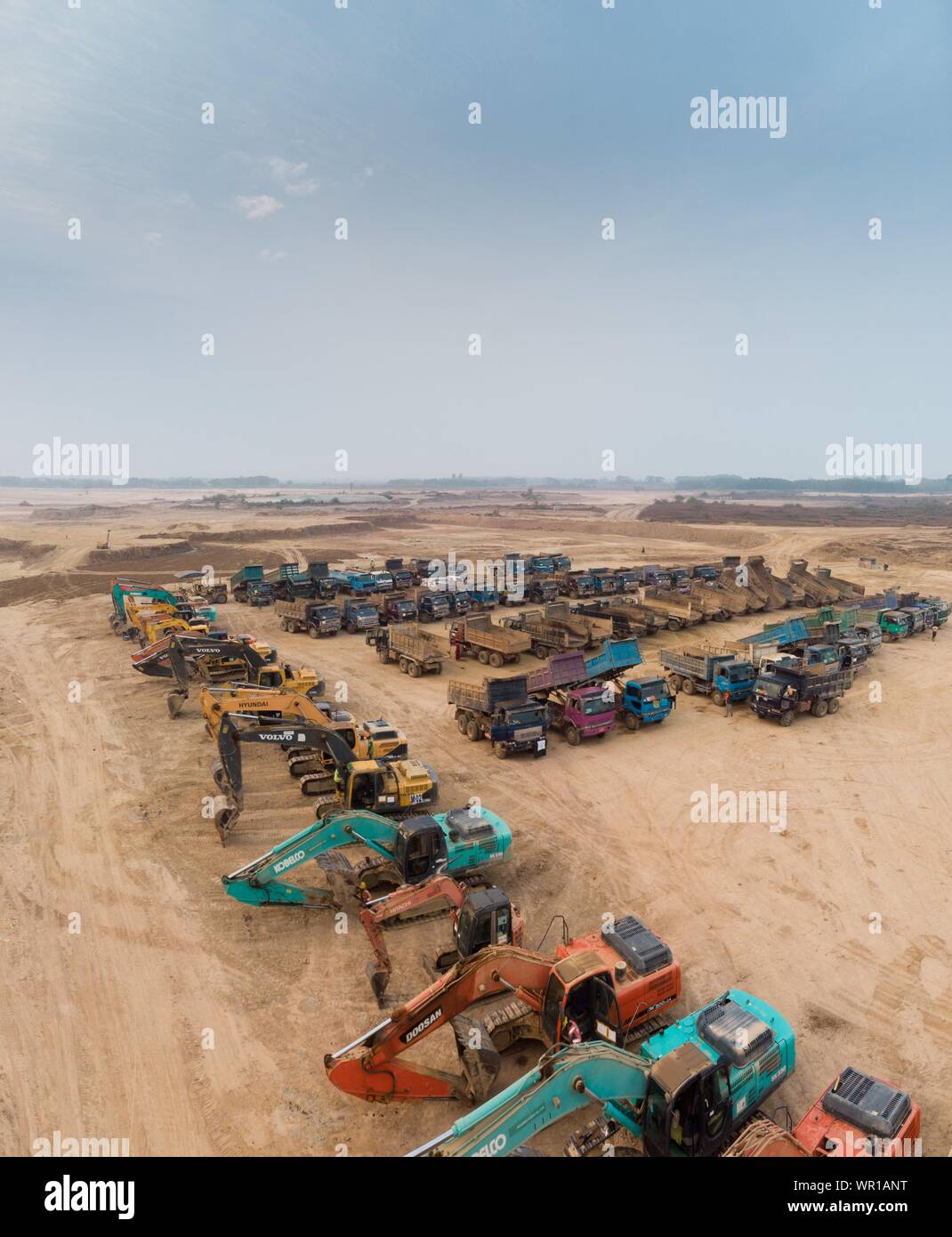 Plan vertical aérien de machines lourdes garées à vide champ sous un ciel dégagé Banque D'Images