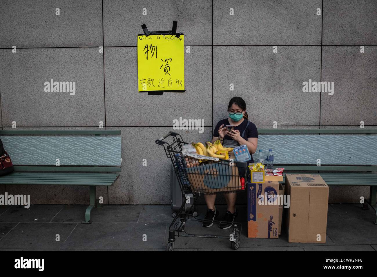 Une femme assise à côté d'un panier et des boîtes de bonne abandonnée par les manifestants pendant les manifestations.Après 14 semaines de protestation, les manifestations ont continué à Hong Kong malgré le retrait par chef de l'exécutif, Carrie Lam d'un sujet controversé projet de loi sur l'extradition. Continuez à prendre les rues manifestations manifestants comme l'exige le gouvernement de la ville à assister à leurs revendications, y compris une enquête indépendante sur la brutalité policière, la rétractation du mot 'riot' pour décrire les rallyes, et le droit pour Hong Kong les gens à voter pour leurs propres dirigeants. Banque D'Images